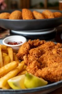 Ración crujiente de chicken fingers con salsa en El Canalla sports bar en Madrid